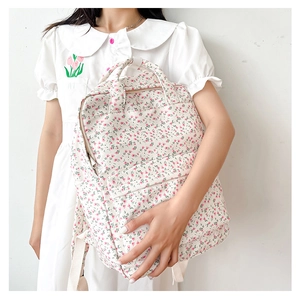 Detail of floral canvas backpack featuring side storage pocket and pink flower pattern