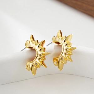 Macro shot of 18K gold sunburst C-shaped earrings with metallic radial spikes