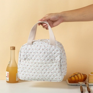 Detalle de bolsa térmica acolchada floral con asas beige y bolsillo delantero