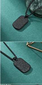 Macro detail of black geometric rhombus pendant with textured pattern and matching chain