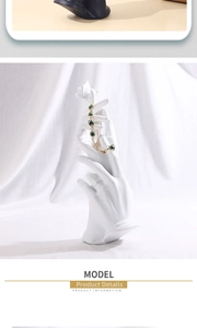 Detail of golden heart hand harness displayed on elegant white resin hand statue