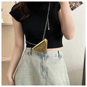 Détail d'un mini sac triangle doré métallisé avec ornement papillon et chaîne fine