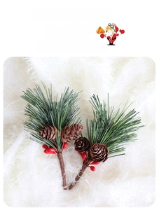Detail of faux pine branch with green needles, brown pine cones and red berries for decor