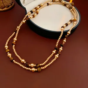 Retro double-layer faux pearl and tiger eye stone necklace on premium leather background