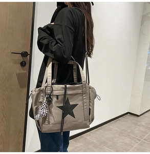 Detail view of water-resistant taupe tote bag with star print and checkered charm