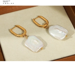 Detail view of Hepburn style earrings with irregular baroque pearls and gold titanium rings