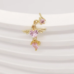 Macro shot of gold L-shaped nose stud with pink heart gem and angel wing detail