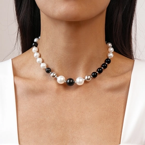Elegant necklace with black and white faux pearls on female model in V-neck top