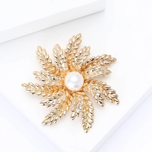 Elegant gold leaf brooch with white pearl on a minimalist white display stand