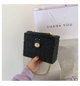 Detail der schwarzen Stroh-Box-Tasche mit goldenem Metalldrehverschluss und Kette
