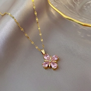 Macro detail of gold four-leaf clover necklace with pink teardrop stones on silk
