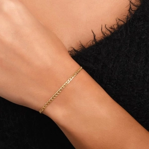 Close-up of a 14k gold-plated slim curb chain bracelet worn on a female wrist