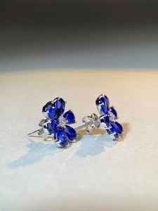 Macro detail of S925 silver flower stud earrings with blue sapphire-like zircons