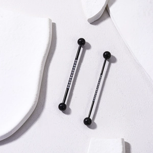 Detail of black industrial barbell piercing with shimmering white cubic zirconia stones