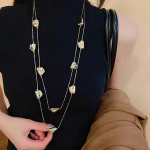 Collana lunga geometrica dorata a doppio strato con ciondoli irregolari su una modella