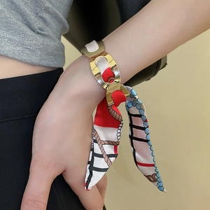 Detailed shot of golden oval metal links intertwined with a colorful silk scarf wrap bracelet