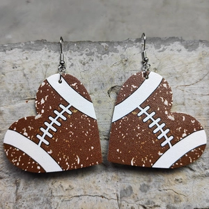 Faux leather heart earrings with brown rugby ball pattern and metal hooks on stone background