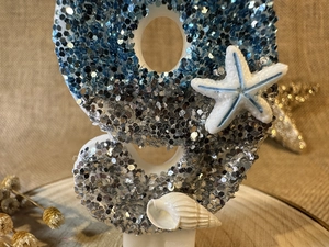 Macro detail of blue glitter ocean number candle with starfish and seashell decorations