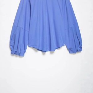 Chemise en popeline bleue pour femme avec manches ballon élégantes et ourlet arrondi