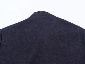 Detailed close-up of dark blue denim twill fabric texture and stitching on the collar