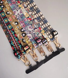 Detail view of long phone strap featuring vintage totem patterns and gold metal buckles