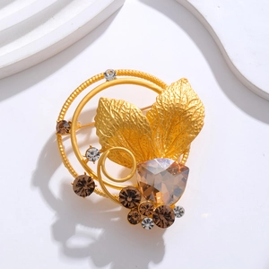 French vintage golden leaf brooch featuring brown and clear crystals on white texture