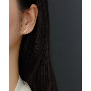 Detail of s925 silver gold piercing earring with square-cut stones on a female ear