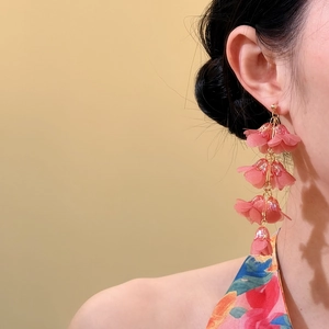 Detailed view of pink lily-of-the-valley tassel earrings worn by a model