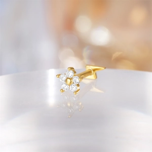 Macro shot of 16G gold floral piercing stud featuring round crystals and a flat back design