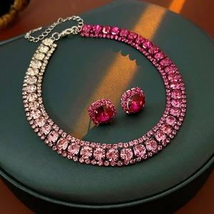 Detailed close-up of pink gradient rhinestone necklace and matching stud earrings on stand