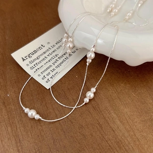 Minimalist 925 sterling silver necklace with white pearls on a decorative white tray