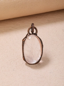 Detailed close-up of a vintage bronze oval pendant featuring a clear natural quartz stone