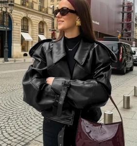 Detail of black faux leather jacket cuff featuring adjustable metal buckle and strap