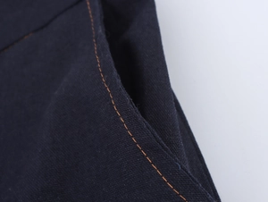 Detailed macro view of orange contrast stitching on navy blue cotton linen fabric