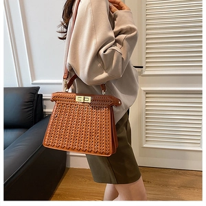 Detail of a brown woven texture handbag with a golden metal clasp and leather strap