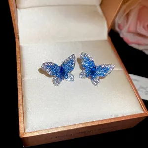 Boucles d'oreilles papillon en argent avec zircons bleus et blancs dans un écrin luxe