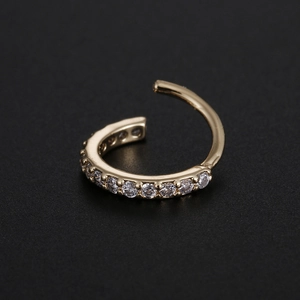 Macro shot of gold-plated copper nose ring with pavé-set white cubic zirconia stones
