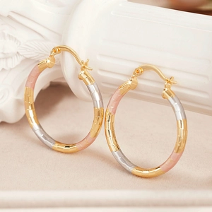 Three-tone hoop earrings with textured diamond-cut facets in gold and silver finish