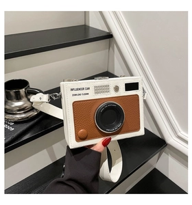 Detail of vintage camera-style crossbody bag with influencer lens design and brown accents