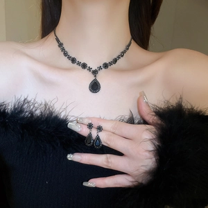Close-up of black teardrop pendant necklace and matching earrings on model neck