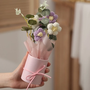 Handheld knitted purple flower bouquet in a pink paper wrap and matching container