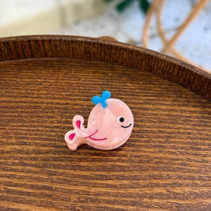 Détail d'une mini pince à cheveux en acétate en forme de baleine rose avec jet d'eau bleu