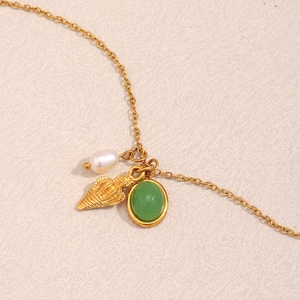 Close-up of 18K gold-plated necklace featuring a white pearl, shell, and green gemstone