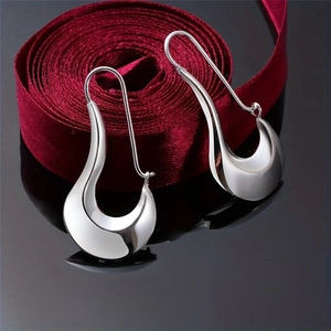 Irregular silver droplet earrings with metallic luster on black mirror background