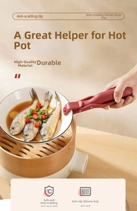 Macro detail of red heat-resistant gripper clip lifting a plate from a steamer pot