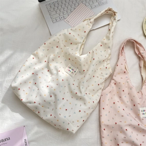 Detail shot of floral canvas tote bags in white and pink on a cozy white bed setting