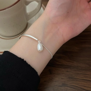 Detail of S925 silver pearl bracelet on wrist with elegant minimalist metal half-cuff