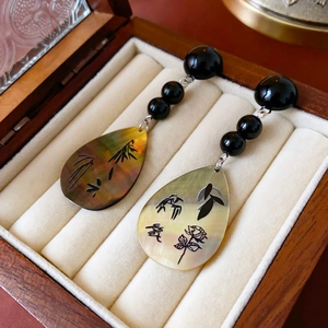 Détail de boucles d'oreilles nacre vintage avec art bambou et kanji amour sur bois