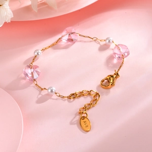 Detailed macro view of the gold-plated chain featuring pink heart crystal and white pearls