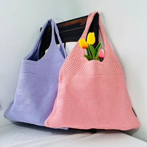Detail of pink and purple knitted heart tote bags featuring textured yarn and floral decor